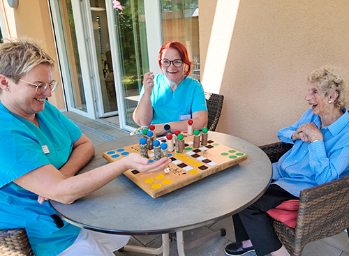 Unsere Pflegekräfte beim gemeinsamen Brettspiel mit einer Dame der Tagespflege.